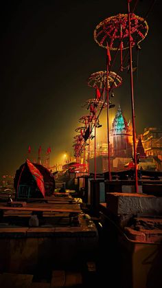 an outdoor area with umbrellas and buildings in the background at night, lit up by brightly colored lights