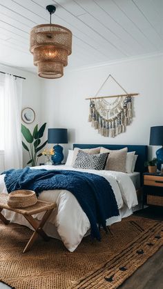 a bedroom with white walls, blue bedding and wicker lamps hanging from the ceiling