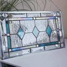 a stained glass purse sitting on top of a white table next to a potted plant