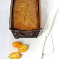 a loaf of bread sitting on top of a white plate next to some oranges