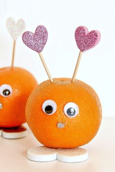 two oranges with sticks sticking out of their mouths and hearts on top of them