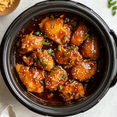 a crock pot filled with chicken and sauce on top of a white tablecloth