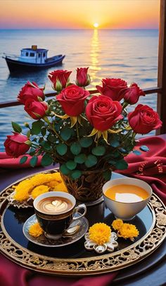 there is a cup of coffee and some flowers on the table next to the ocean