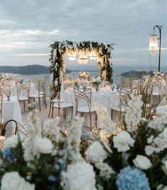 an outdoor dining area with tables and chairs set up for a formal function on the beach