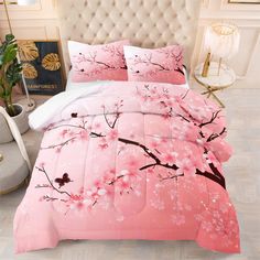 a bed with pink comforter and pillows on it in a room next to a plant