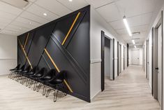 an office hallway with black chairs and yellow lines on the wall, along with white walls