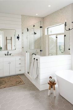 a white bathroom with two sinks, mirrors and bathtub in the middle of it