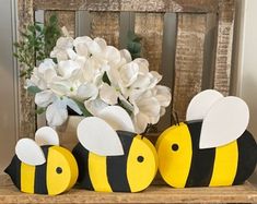 three yellow and black bees sitting on top of a wooden shelf next to white flowers