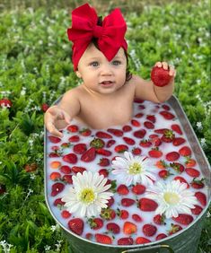 a baby in a tub with strawberries and daisies