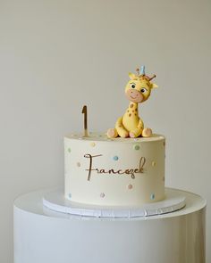 a white cake with a giraffe on top and the word fancy spelled in gold