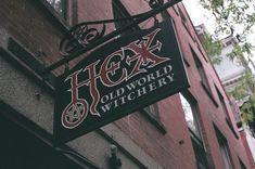 the sign for hog's old world witchery hangs from the side of a brick building