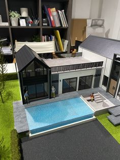 a model of a house with a pool in the middle and two people standing outside