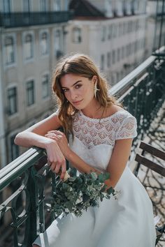 a woman in a white dress sitting on a balcony with her hand on the railing