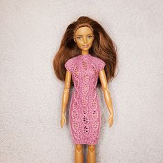 a doll with long hair wearing a pink knitted dress and heels on a white surface