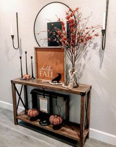 a wooden table topped with a vase filled with red flowers and candles next to a mirror