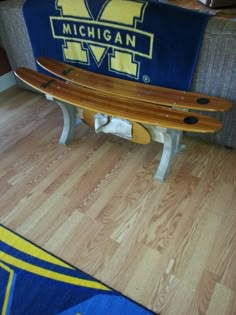 a wooden bench sitting on top of a hard wood floor next to a blue and yellow blanket