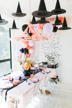 a party table with black and white balloons, pink and orange decorations, and candles