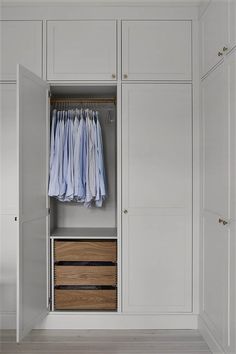 an open closet with clothes hanging on hangers and two wooden drawers in front of it