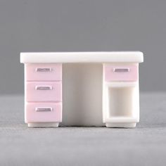 a miniature pink and white desk with drawers