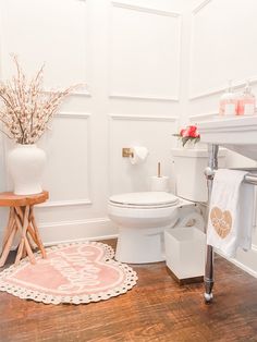 a white bathroom with pink rugs on the floor and a toilet in the corner