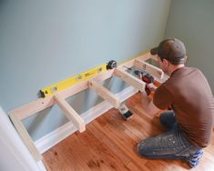 a man sitting on the floor working on a wooden shelf with tools in front of him