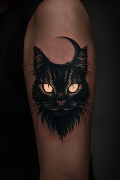 a black cat with glowing eyes and a crescent moon tattoo on the right upper arm