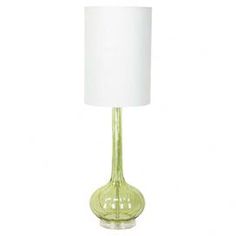 a green glass table lamp with a white shade on the base and a light bulb attached to it