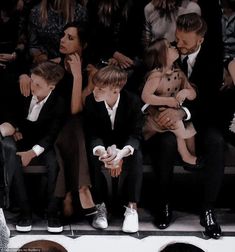 a group of people sitting next to each other in front of a crowd at a fashion show