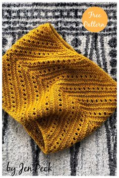 a yellow knitted blanket sitting on top of a bed next to a black and white rug