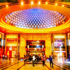 people are standing in the lobby of a large building with a domed ceiling and colorful lights