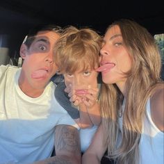 two women and a man are posing for a photo with their tongue sticking out in front of them