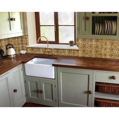 a kitchen with green cabinets and wooden counter tops, white sink and dishwasher