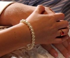 two people holding each other's hands while wearing pearls on their bracelets and rings