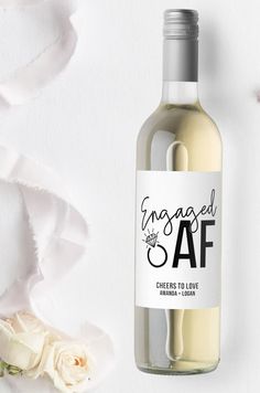 a bottle of wine sitting next to a white rose