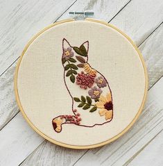 a cat with flowers on it's back sitting in front of a hoop