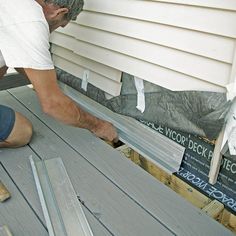 a man working on the side of a house with wood planks being laid out