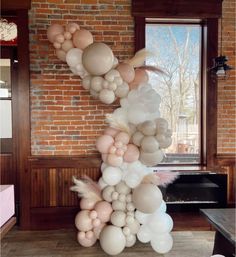 balloons and feathers are arranged in the shape of a letter on a table next to a brick wall