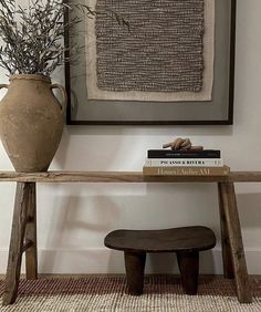 a wooden bench sitting in front of a wall with a vase on top of it