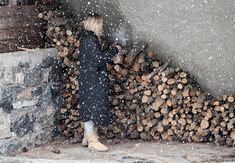 a woman standing next to a pile of logs