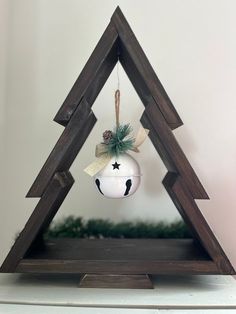 a christmas ornament hanging from the side of a wooden triangle on top of a shelf