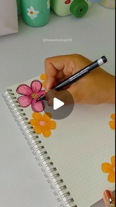 a person is drawing flowers on a notebook