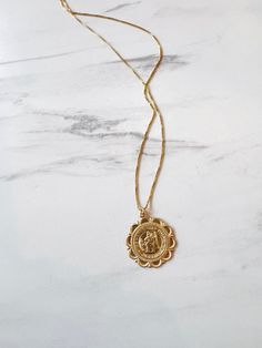 Our timeless Protector St. Christopher Necklace is the symbol of protection and guidance. The Protector St. Christopher Necklace is the perfect accessory for those who seek protection and blessings through life. A travel protection medallion, this pendant and necklace is made of high quality 14K gold fill. Saint Christopher is the patron saint of travelers, keeping them safe on their journey. Charm says "St. Christopher Protect Us" Pendant measures 22mm in diameter. The. medallion hangs on an ad St Christopher Necklace The Catholic Company, St Christopher Necklace, Symbol Of Protection, French Collection, St Christopher, Saint Christopher, The Protector, Forever Jewelry, Patron Saints