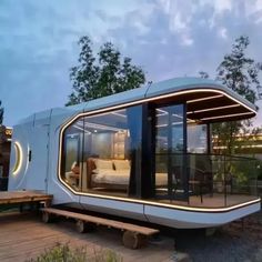 a house shaped like a boat with windows and lights on the outside, sitting on top of a wooden platform