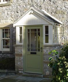 a stone building with a green door and window