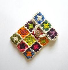 a crocheted square with flowers is shown on a white surface, and has a button in the middle