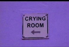 a sign that says crying room with an arrow pointing to the right on a purple wall