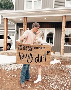 a man and woman holding a sign that says, you can't buy happiness but you can buy dirt