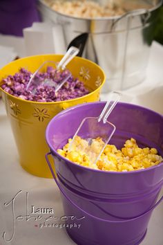 two buckets filled with popcorn sitting on top of a table