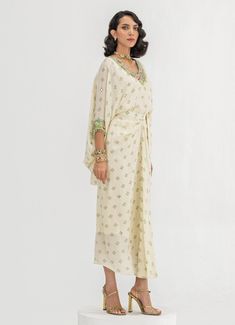 This elegant Ivory Embroidered Toga Cape Skirt Set is a timeless blend of sophistication and comfort. Crafted from soft crepe fabric, the set features a Ivory-colored, loose-fitting cape adorned with intricate floral embroidery around the neckline and cuffs. Paired with a wrap-style skirt that accentuates the waist and drapes effortlessly, it creates a flattering fit while ensuring easy movement. Ideal Indo-Western attire for home poojas, family gatherings, or festive occasions. Composition : Top and Skirt - Crepe Care: Dry Clean Only and Vacuum Storage This product can be customized for sleeves, blouse length and neckline Delivery : 4-6 weeks as the product is hand crafted. Check Size Guide or choose MySize for free customisation (All Sizes above XL can be made at 15% additional cost) For Traditional Cream Dress With Pearl Embroidery, Elegant Georgette Dress With Embroidered Border, Beige Embroidered Dress With Traditional Drape, Traditional Off-white Georgette Dress, Traditional Off-white Dresses With Pearl Embroidery, Traditional Off White Dress With Pearl Embroidery, Summer Silk Sets In Cream Color, Summer Silk Sets In Cream, Cream Silk Sets For Summer