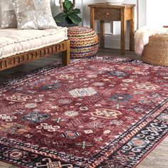 a large red rug in a living room next to a couch and table with pillows on it